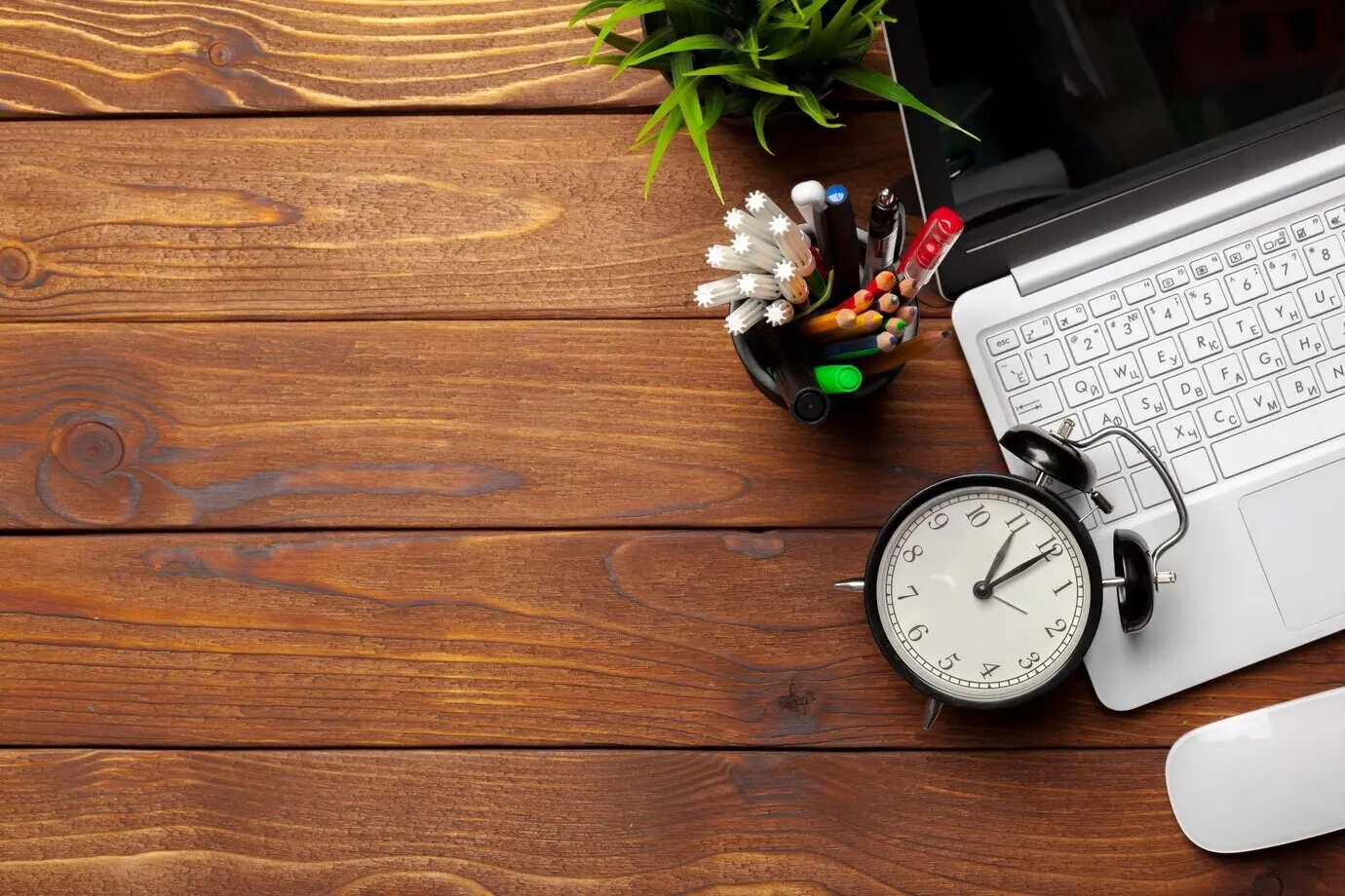 A laptop and a notebook on a wooden work desk.
