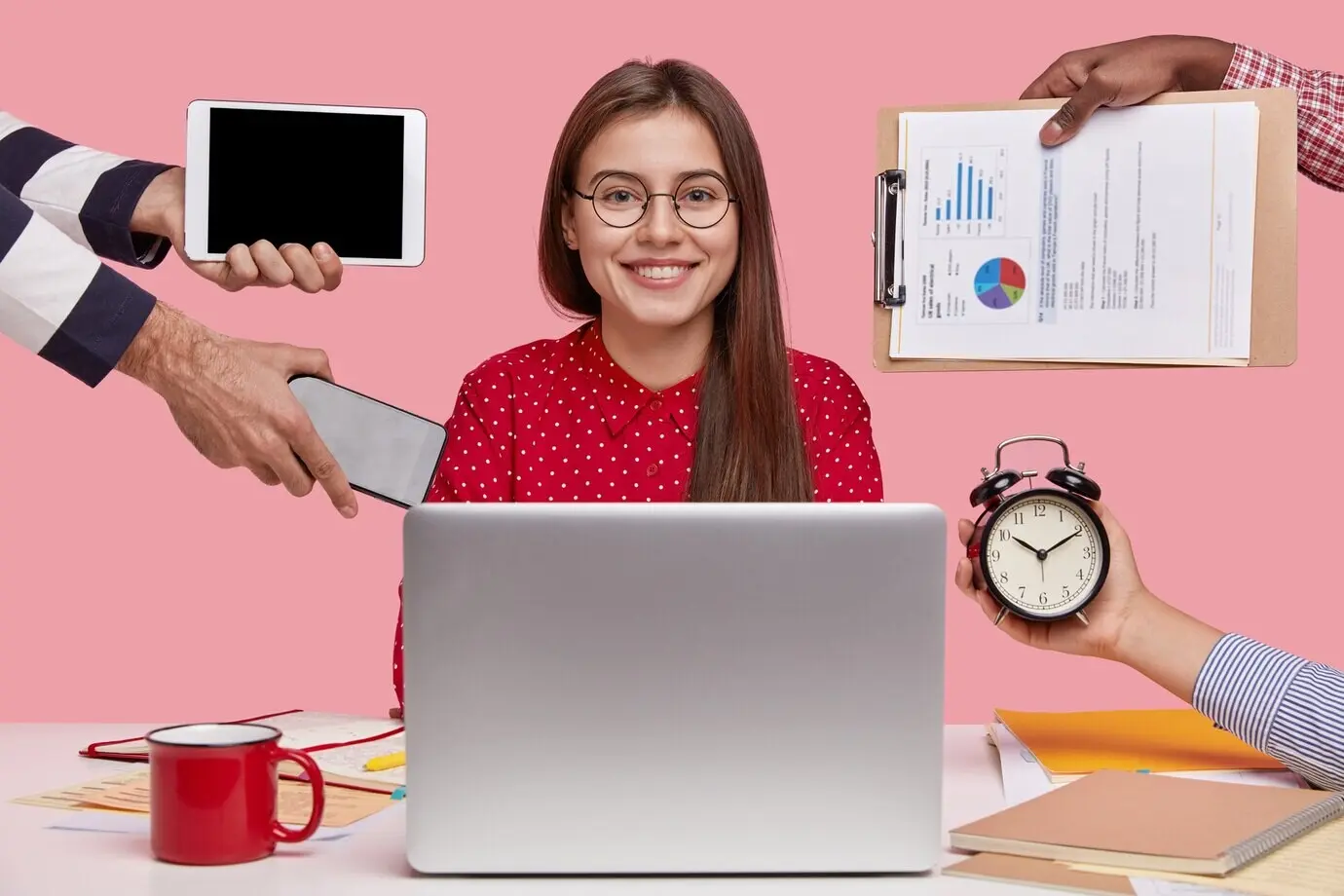 Horizontal shot of a beautiful, smiling woman in a red shirt sitting in front of an open laptop computer.